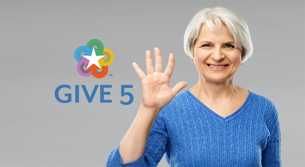 Smiling woman in a blue sweater holding up five fingers next to 'Give 5' logo with colorful star design on gray background.